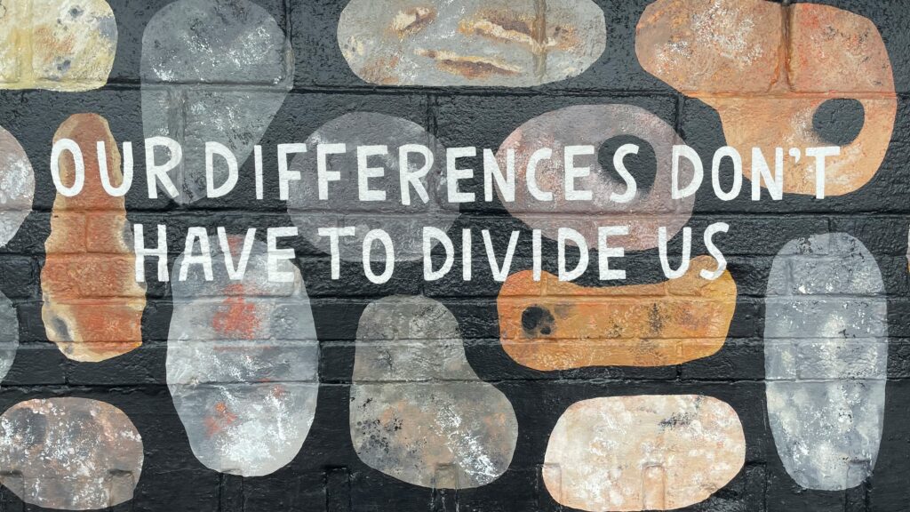 Spray-painted wall with writing that says “Our differences don’t have to divide us”